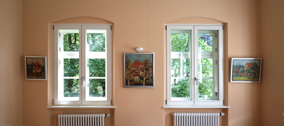 Blick in die Ausstellung Konrad Sommer: Ein bayerischer Maler aus Moosach, München 2024, Gruppensaal, drei Gemälde mit Häusern der Siedlung Hartmannshofen 